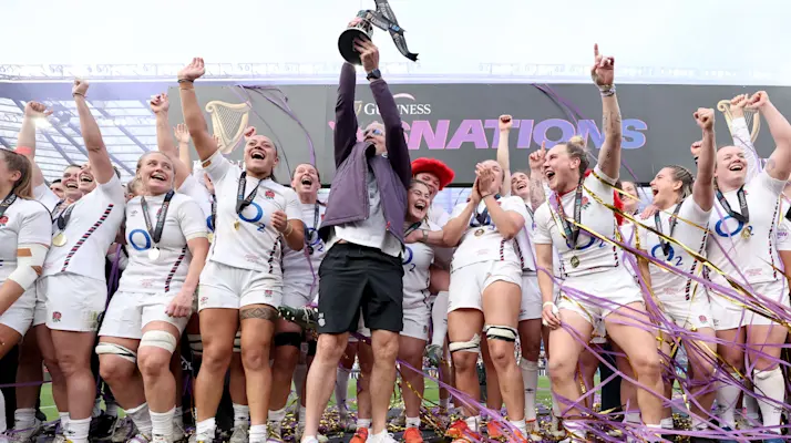 John Mitchell lifts the 2025 Championship trophy, surrounded by the Red Roses squad.