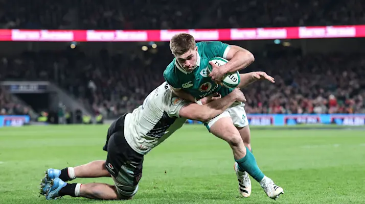 Ireland's Jack Crowley scores a try despite Wales' Ben Carter's efforts during the 2026 Guinness Six Nations Championship Round 4 game between Ireland and Wales in the Aviva Stadium, Dublin, I