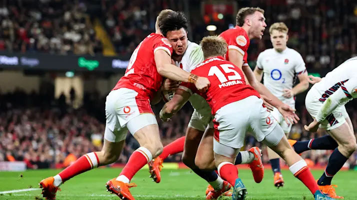 England's Marcus Smith is tackled heavily by the Welsh defence during the 2025 Guinness Men's Six Nations Championship
