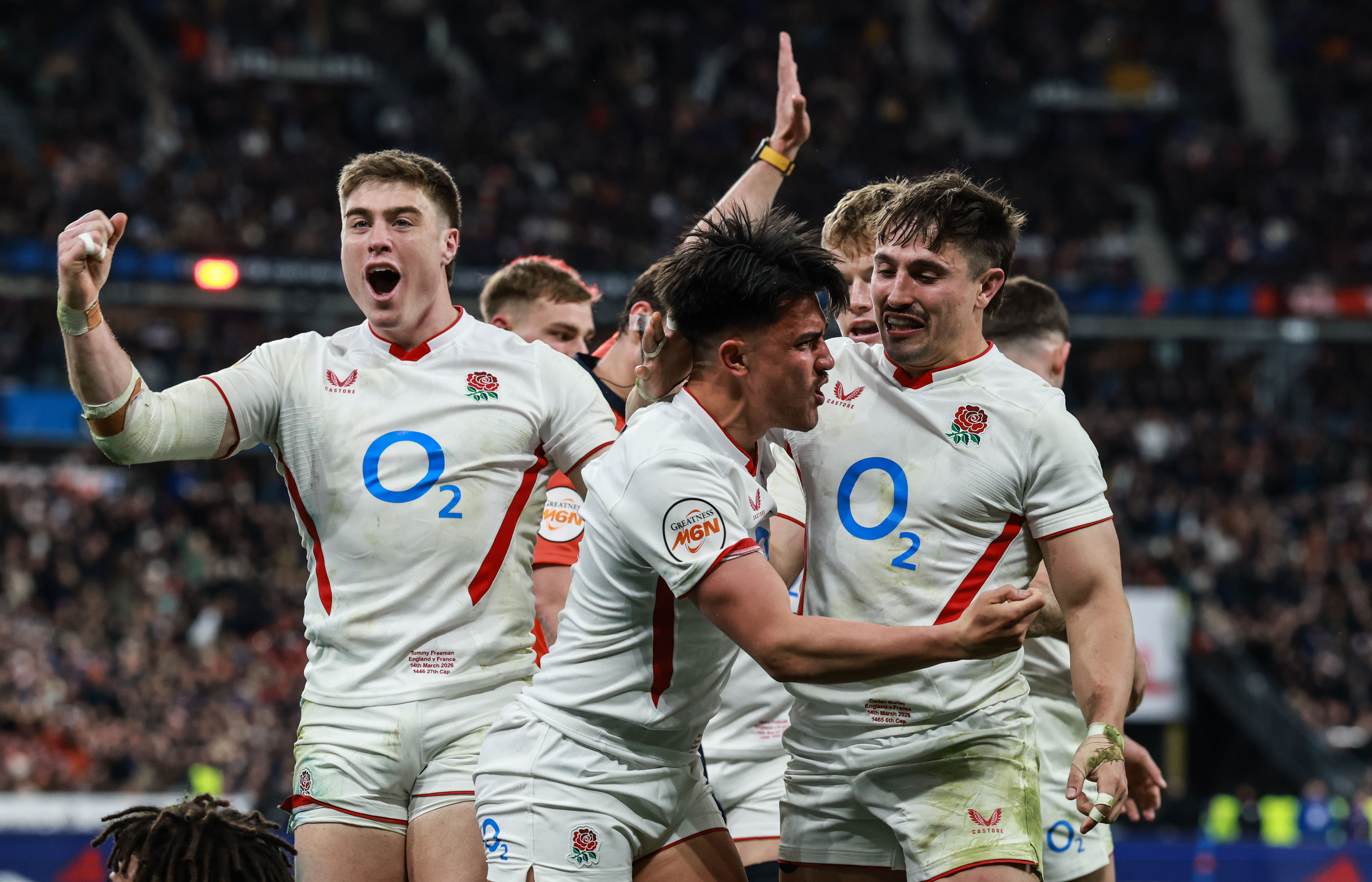 England's Marcus Smith celebrates scoring a try with Tommy Freeman and Cadan Murley during the 2026 Guinness Six Nations Championship Round 5 game between France and England in Stade de France.