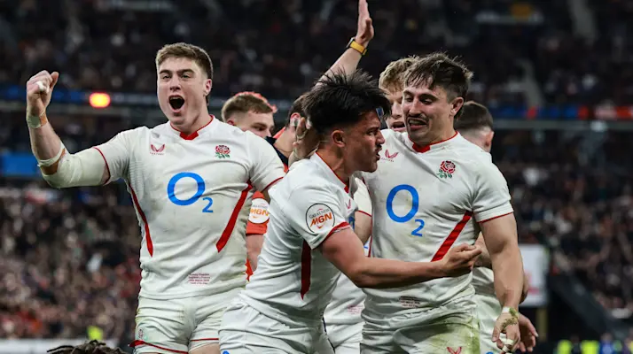 England's Marcus Smith celebrates scoring a try with Tommy Freeman and Cadan Murley during the 2026 Guinness Six Nations Championship Round 5 game between France and England in Stade de France.