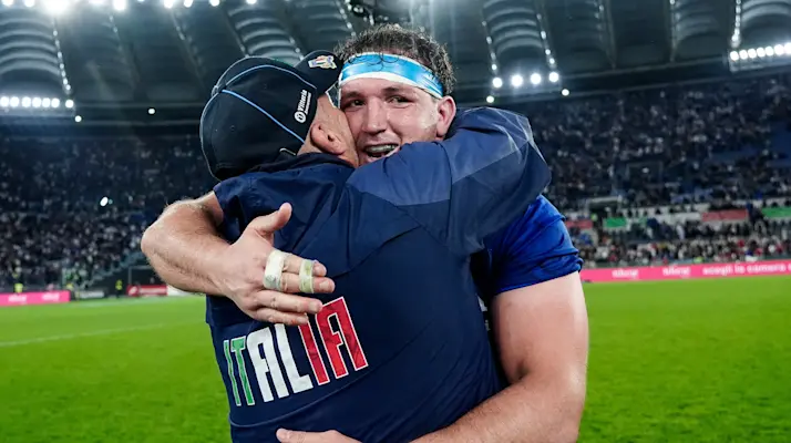 Captain Michele Lamaro is hugged by one of the team's coaching staff after the history-making victory against England in the 2026 Championship.