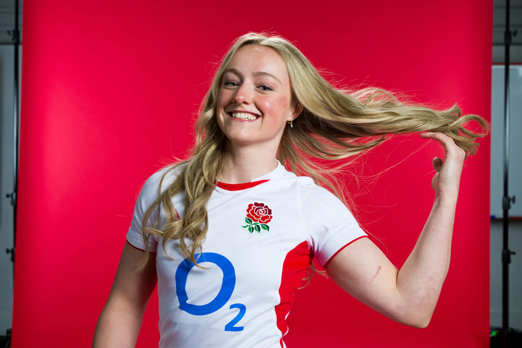 Millie David poses in England kit against a red backdrop.