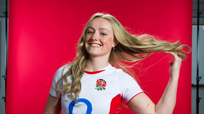 Millie David poses in England kit against a red backdrop.